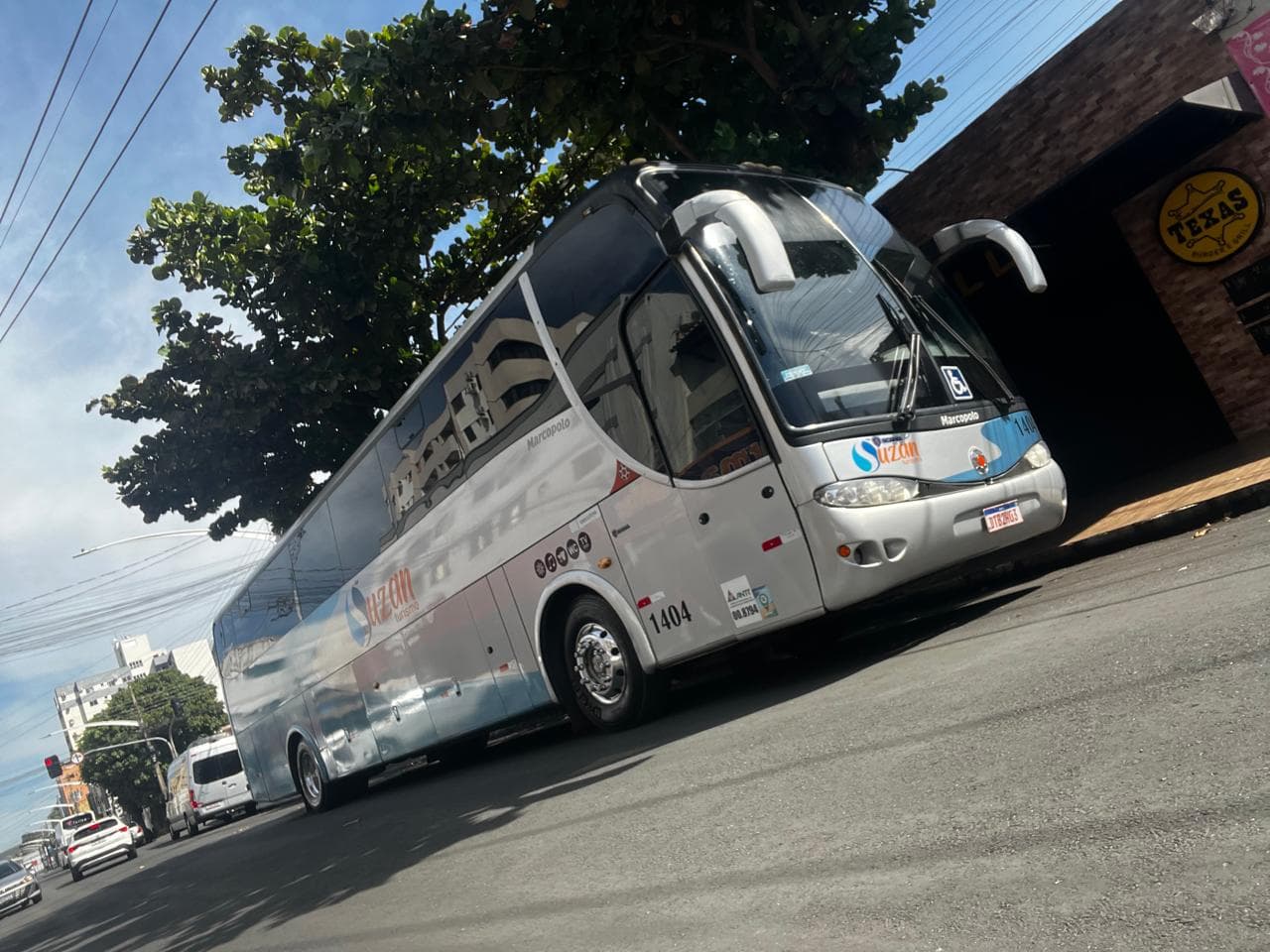 Ônibus Marcopolo da Suzan Turismo em rua arborizada, visto de frente