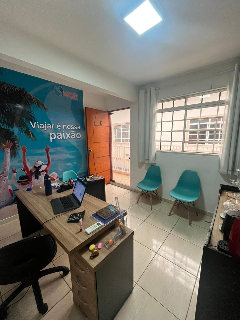 Interior da loja da Suzan Turismo em Taguatinga, com mesa de atendimento e painel de praia